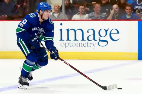 A Vancouver Canucks player skating past an Image Optometry ad on the rink boards